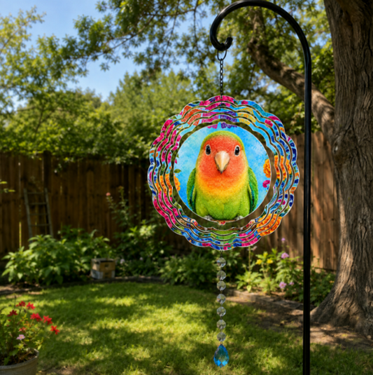 A colorful metal garden suncatcher featuring a cartoon lovebird, hanging from a black metal garden stake in a backyard garden setting.